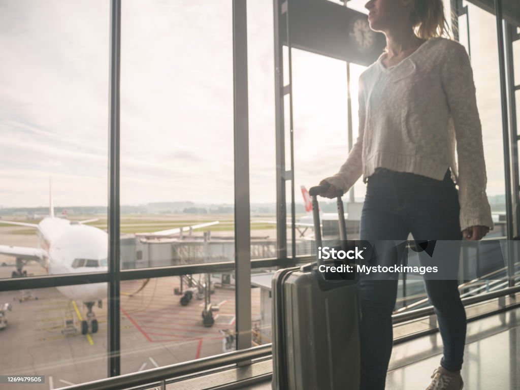 Woman with hand luggage walking in airport Woman getting ready to board the plane Zurich Airport Stock Photo
