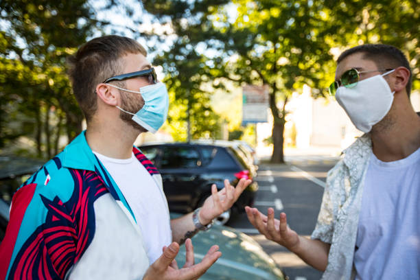 istock Young Adult Men Having a Discussion on Parking Lot While Wearing Protective Masks 1269479582
