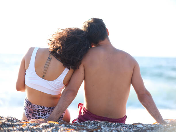 Young couple sitting on beach back view