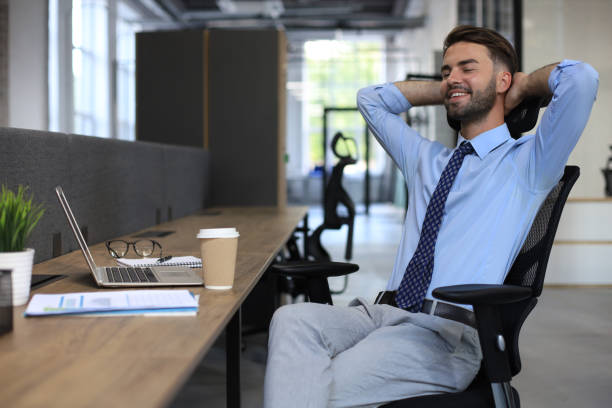 istock Young modern business man keeping hands behind head and smiling while sitting in the office. 1269484041