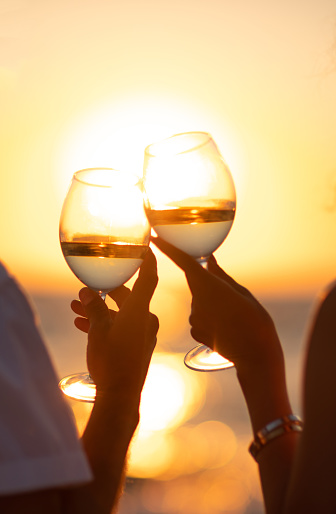 Silhouette of two hands clinking white wine glass