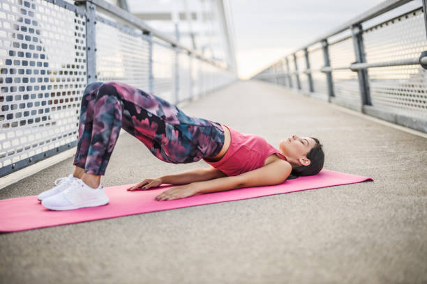 молодая спортивная женщина, практикующая йогу, делающая упражнения dvi pada pithasana, поза glute bridge, тренировка, ношение сп�ортивной одежды, на откры� - dvi стоковые фото и изображения