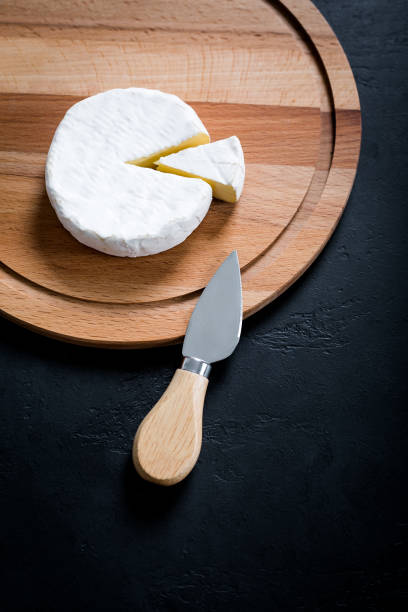istock Sliced Camembert with knife on cheese platter on black background, 1269494000