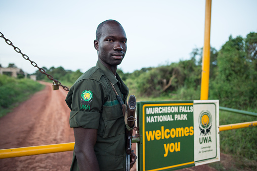 Masindi / Uganda - September 25, 2016: Ranger in Murchison Falls National Park armed with AK47 rifle guards the entrance gate to the park in Uganda