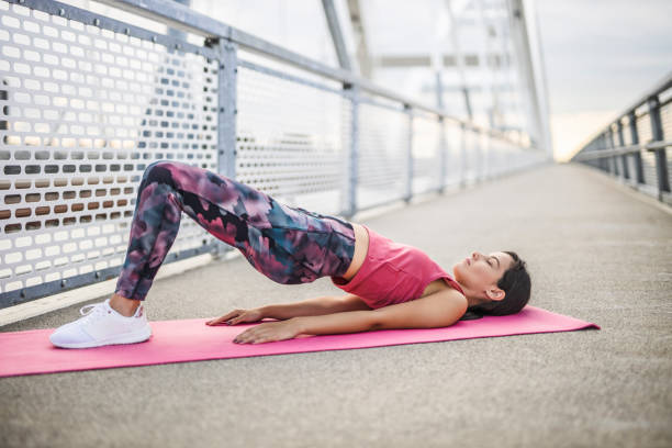 joven mujer deportiva practicando yoga, haciendo ejercicio dvi pada pithasana, postura de glute bridge, ejercicio, usar ropa deportiva, al aire libre - dvi fotografías e imágenes de stock