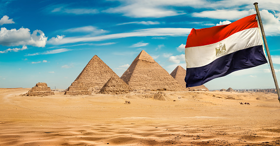 Pyramids of Giza in the desert by day and egyptian flag