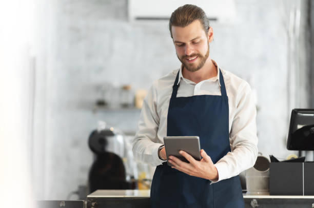 Hipster barista male using digital tablet in the modern cafe.
