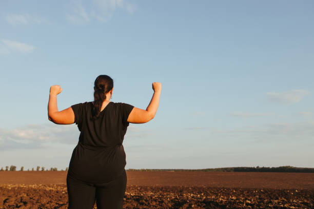 istock Overweight woman rising hands, view from the back 1269501510