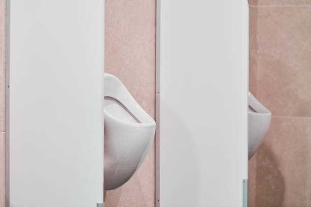 Urinal in public men toilet. Urinal with privacy barriers and flush control sensor in shopping center. WC toilet room.