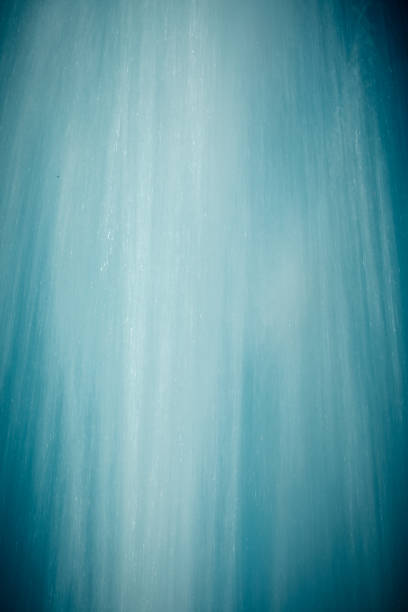 Image of a water fountain photographed close up with a long exposure against a blue sky creates an abstract background.