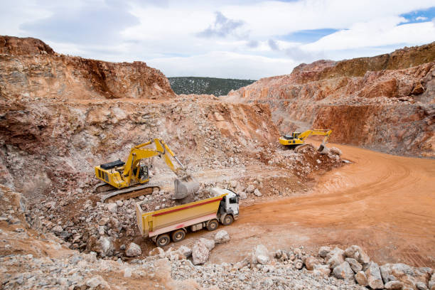 Construction machinery working in a quarry Excavators are loading dumper truck in a quarry. camel colored photos stock pictures, royalty-free photos & images