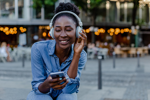 Young African American woman with headphones using smart phone outdoors