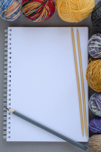istock Background with multicolored yarn balls and notebook with pencil and knitting bamboo needles on gray background. Craft, handmade, hobby concept. Copy space, top view 1269508840