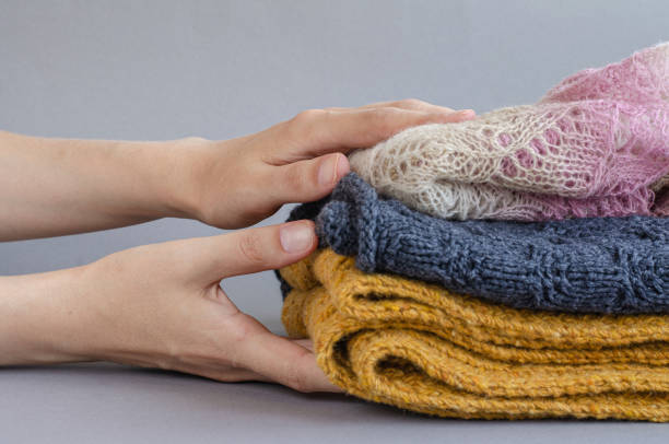 istock Woman holding stack of folded warm wool knitted clothes on gray background 1269509421