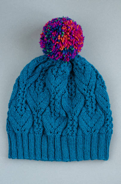 istock Beautiful kace handknitted hat with multicolored pompon on gray background. Top view 1269509488