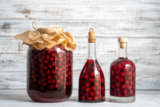 eigengemaakte tinctuur van rode kers. berry alcoholische dranken concept. rode wijn die van rijpe kersen in glasflessen en potten in de oekraïne wordt gemaakt - druppelfles stockfoto's en -beelden