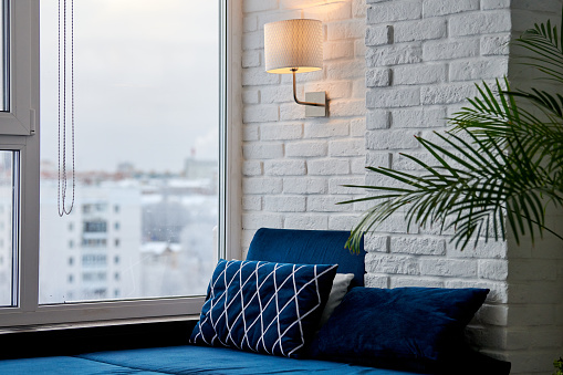 Modern loft apartment with sofa and window view on cityscape. Stylish luxury room in cozy house for rent.