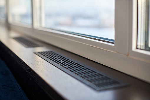 Windowsill, heating grid ventilation. Winter apartment heating. Modern double glazed windows