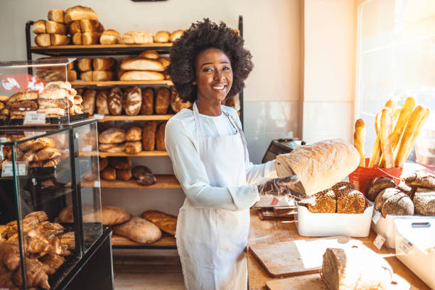 istock Smiling baker woman standing with fresh bread at bakery. 1269519489