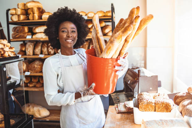 istock Smiling baker woman standing with fresh bread at bakery. 1269519757