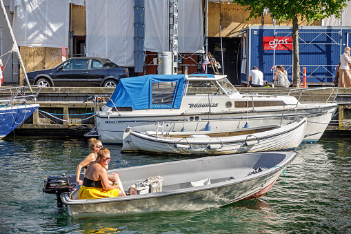 Christianshavn, Copenhagen, Denmark, August 7, 2020: Two women in a small speedboat on a warm day on an old channel in the center of the Danish capital