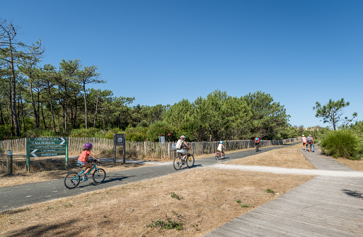 Carcans, France - 08-05-2020: a family rides on the cycle path that leads from Bordeaux and Lacanau to Maubuisson and Carcans in the Médoc, on the Atlantic coast.