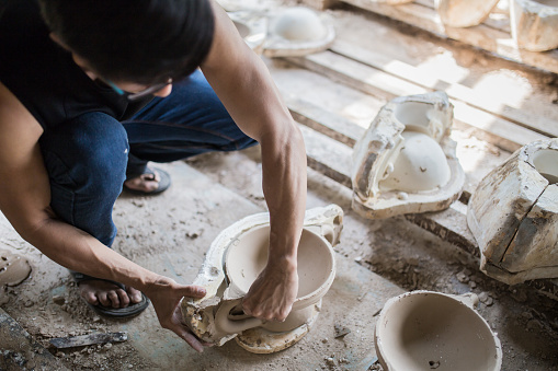 Chinese mature man isolating ceramic from mold in his workshop