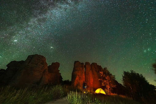 Outdoor hikers hold up lights in the mountains to find the way to the Milky way.The Milky Way crosses the stone forest of ashhatu, Inner Mongolia, China