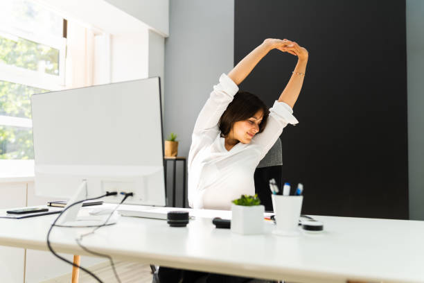 istock Woman Stretches At Office Desk 1269531597