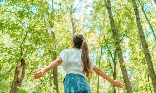 自由な女性は自然の森の中できれいな空気を呼吸します。幸せの両手を広げて後ろから幸せな女の子。新鮮な屋外の森、ウェルネス健康的なライフスタイルのコンセプト。 - nature ストックフォトと画像