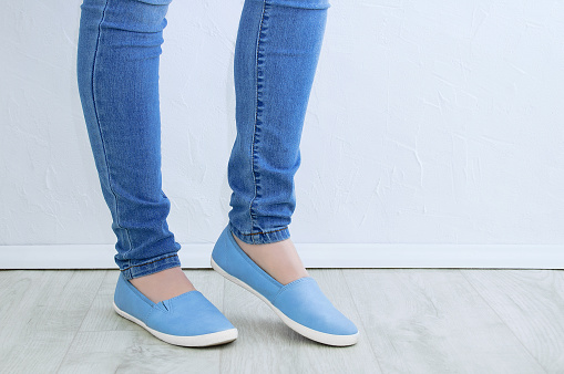 Clothes and footwear. Legs of a caucasian woman in skinny jeans and blue shoes close up.