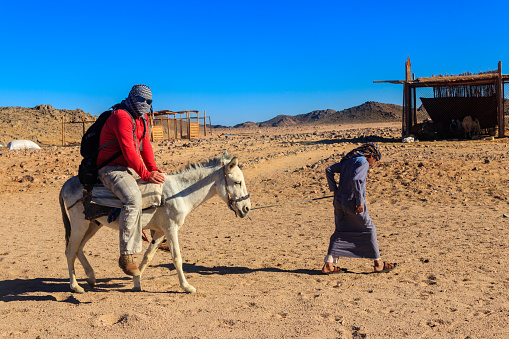 Hurghada, Egypt - December 10, 2018: Tourist ride a donkey in Arabian desert, Egypt