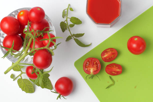 istock Flat lay fresh organic tomatoes with a branch close-up and cutting board on a white background, bright natural color. 1269539109