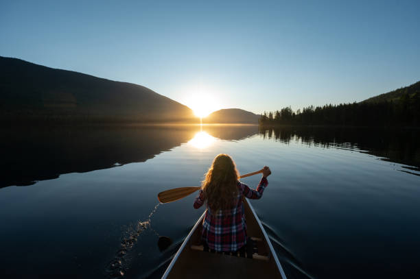 Woman canoeing on a stunning mountain lake stock photo