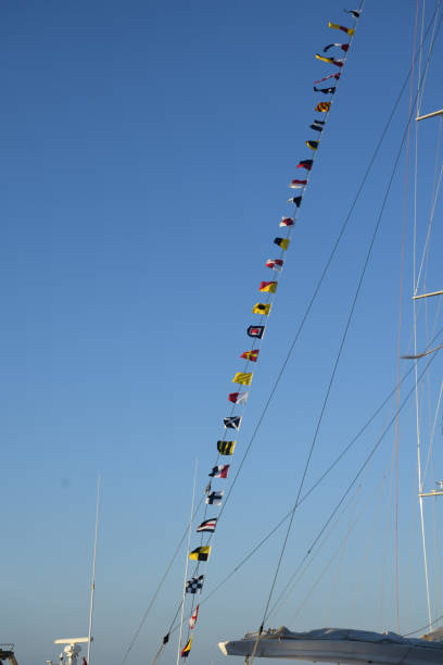 Flags of different countries hanging on the mast of a sailboat in Ibiza