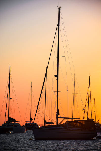 Silhouette of an anchored group of boats at a cove in Ibiza during sunset