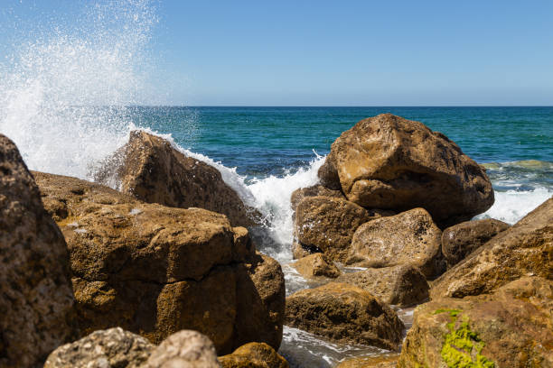 Splashes from a wave splashing on the rocks in sunny day.