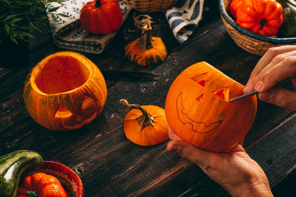 istock Man Carving Spooky Face on a Pumpkin For Halloween 1269548011