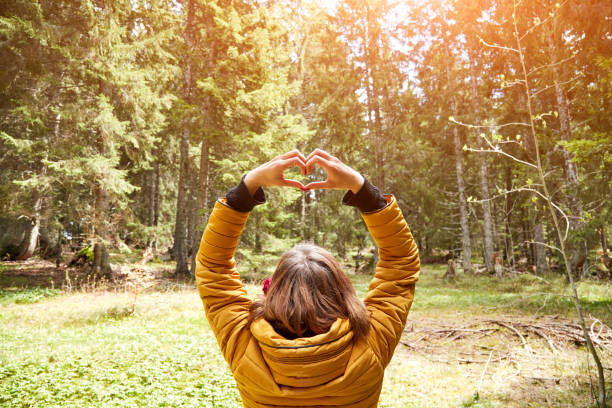 mujer con símbolo en forma de corazón que se sostiene en el aire en el entorno natural. - heart shape loneliness women praying fotografías e imágenes de stock