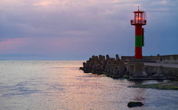 istock Lighthouse protected by concrete breakwater tetrapods at sunset. 1269550605