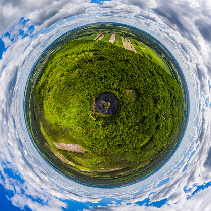 Round lake with island in the middle among forest, little planet aerial view