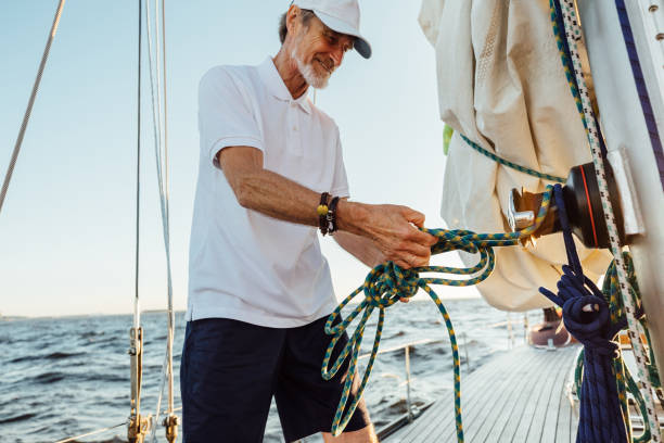 istock Smiling senior man standing on sailboat deck and adjusting rope 1269555935