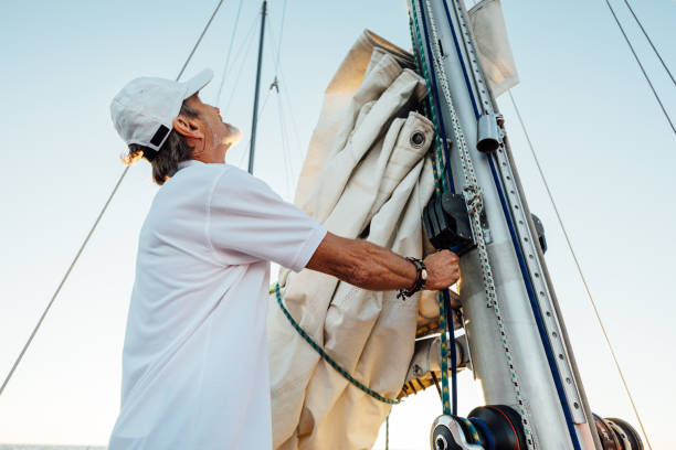 istock Mature captain looking up while adjusting sail. Senior yachtsman preparing a boat for a vacation trip. 1269555957