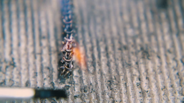 person uses brush to descale heated chain extreme closeup
