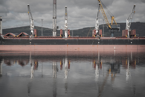 Bulk coal carrier and its reflection at a commercial dock within Belfast Harbour unloading its cargo.  Belfast, Northern Ireland.