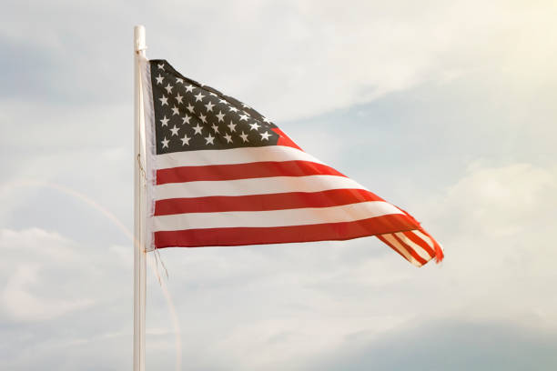 istock American flag on a blue sky with clouds background 1269556615