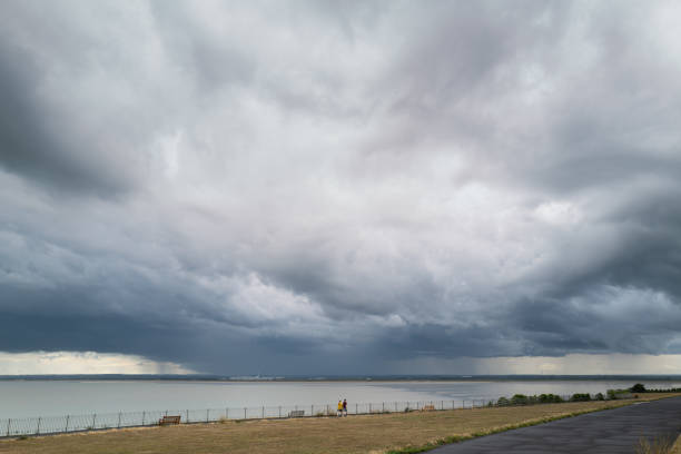 nuages d’orage au-dessus de la baie de sandwich vu de l’esplanade de falaise ouest dans ramsgate. deux personnes marchant sur la promenade semblent minuscules contre la houle du nuage. - ramsgate photos et images de collection