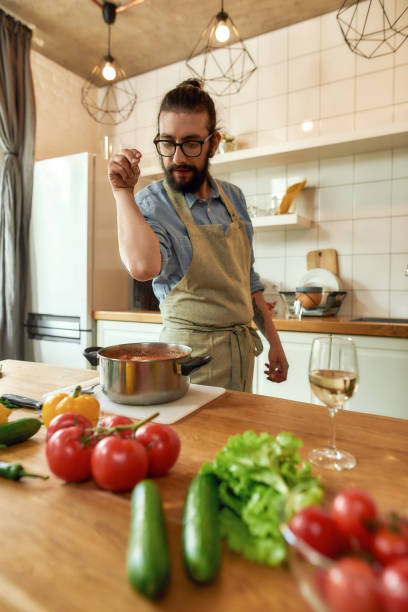 istock Italian man adding pepper, spice to the soup while preparing a meal in the kitchen. Cooking at home, Italian cuisine 1269562491
