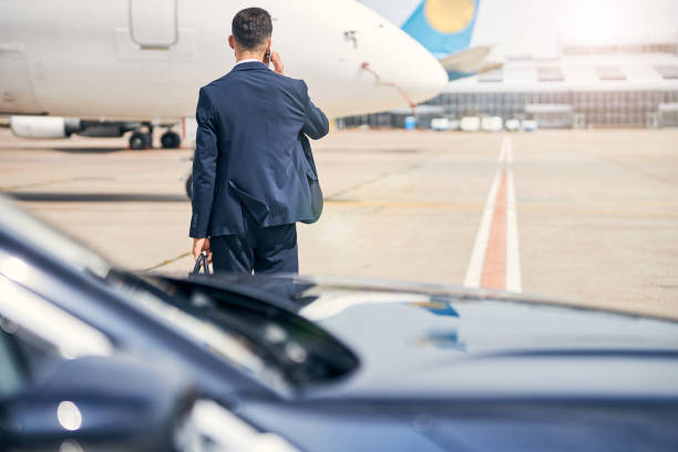 istock Well-dressed man talking on the phone walking towards a jet 1269570269