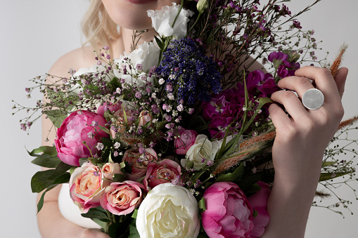 Close up of lady with ring on her hand holding beautiful flowers with bright colored petals